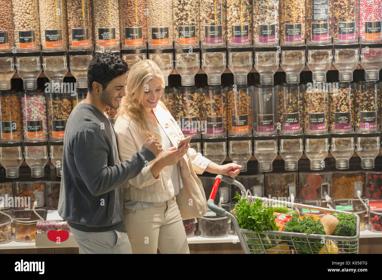 Young couple using cell phone, grocery shopping in market Stock Photo