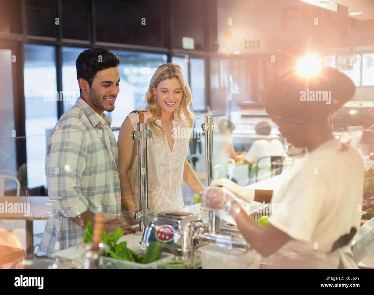 Female worker helping young couple at deli counter in grocery store