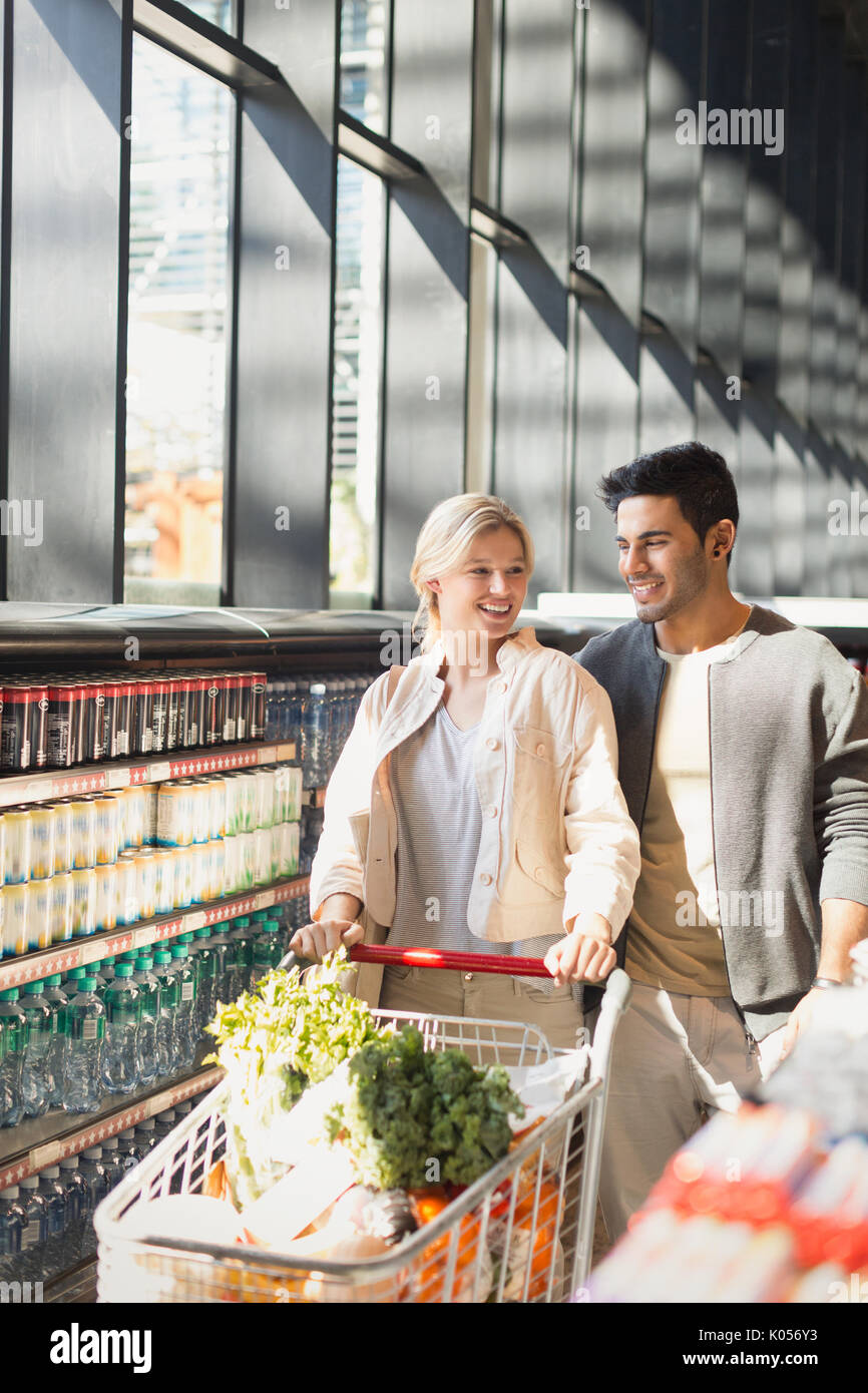 Young couple pushing shopping cart in grocery store market Stock Photo