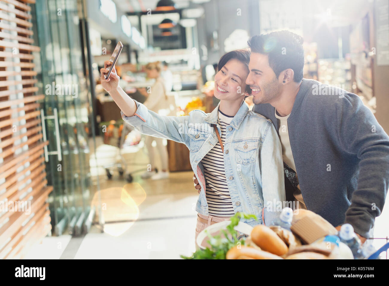 Young couple taking selfie grocery shopping in market Stock Photo