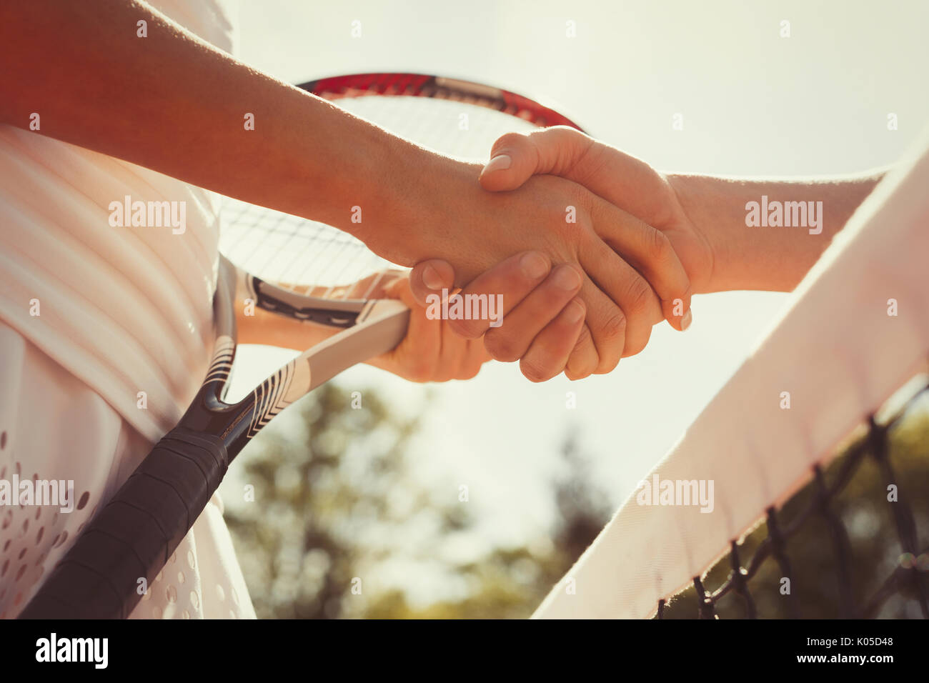 Close up tennis players handshaking in sportsmanship at net Stock Photo