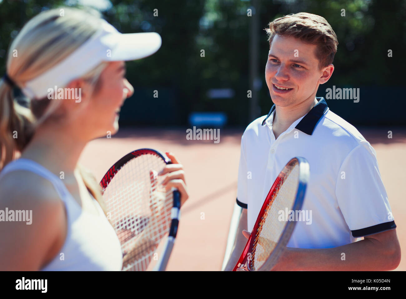 Male and female tennis players talking, holding tennis rackets Stock Photo