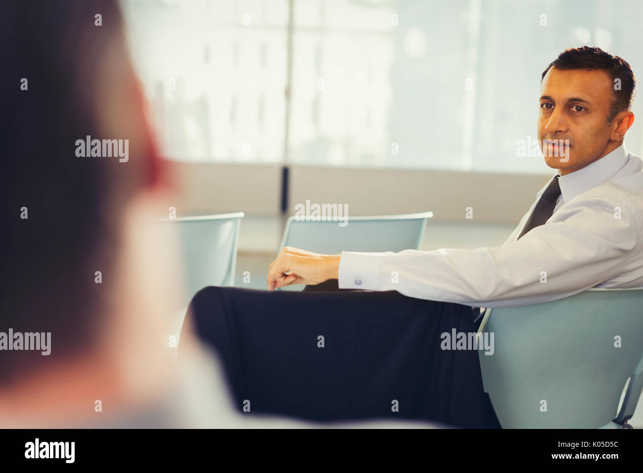 Businessman turning, looking back and listening in conference audience Stock Photo