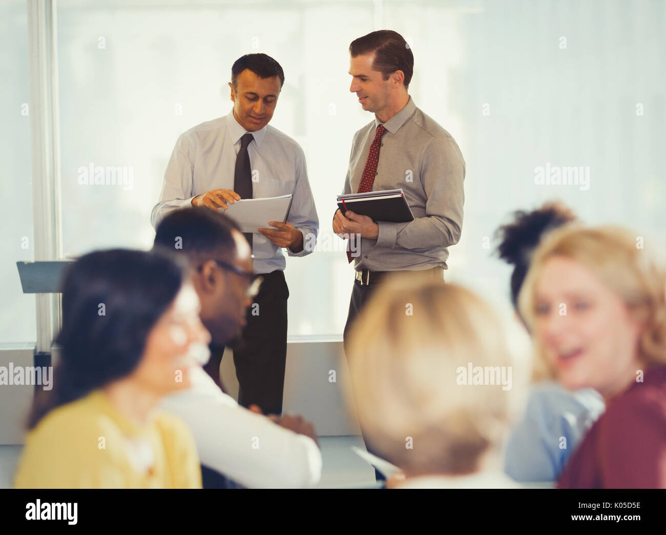 Businessmen discussing paperwork at conference Stock Photo