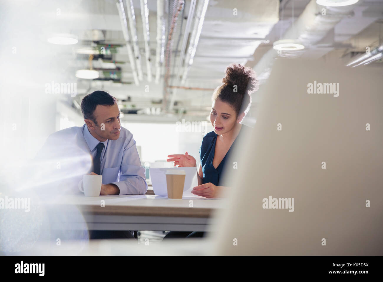 Businessman and businesswoman discussing paperwork in office meeting Stock Photo