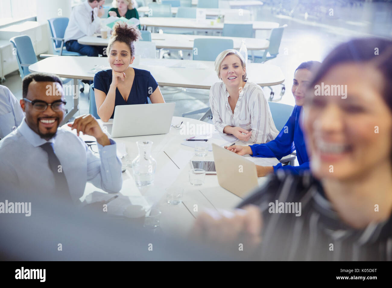 Business people with laptops listening in conference room meeting Stock Photo