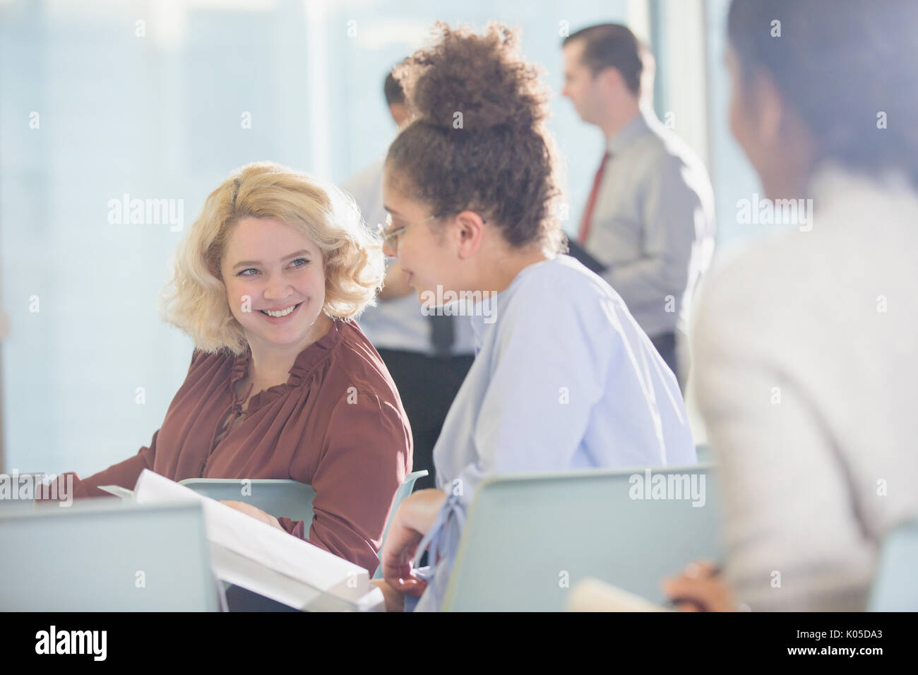 Businesswomen discussing paperwork in conference audience Stock Photo