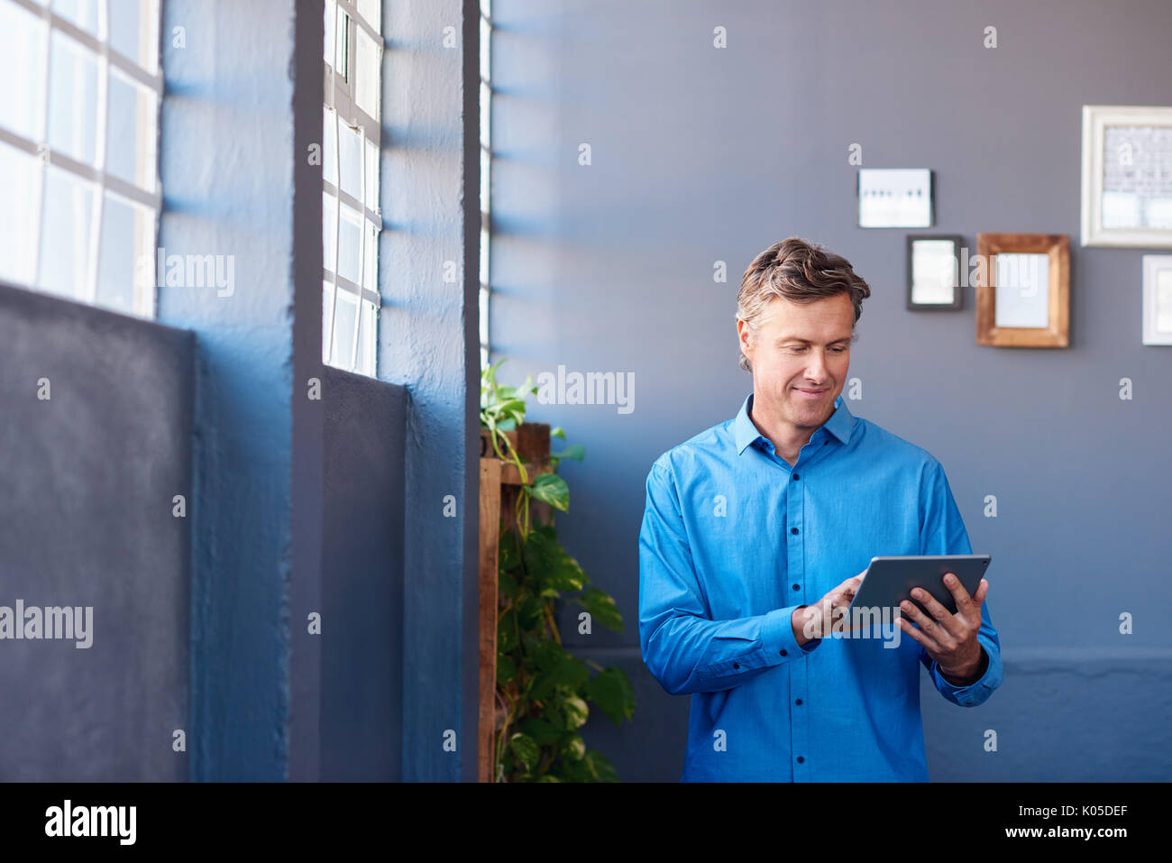 Businessman standing in an office using a digital tablet Stock Photo