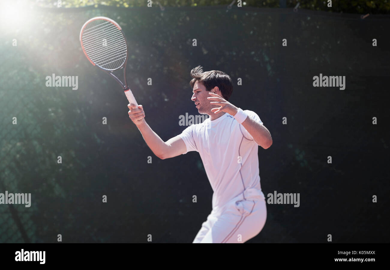 Young male tennis player playing tennis, swinging tennis racket Stock Photo