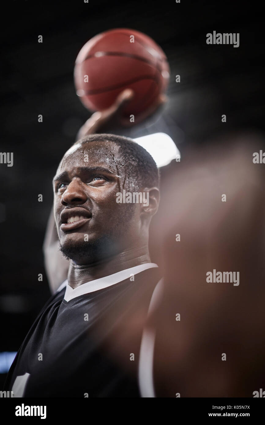 Serious, sweating basketball player holding basketball overhead Stock Photo Alamy