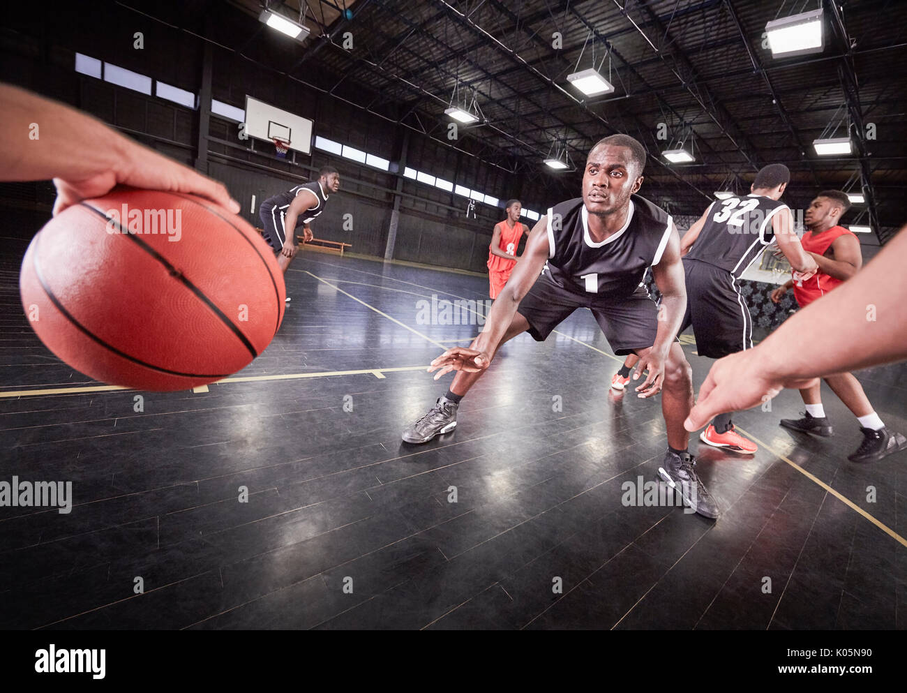 Young male basketball players playing game on court in gymnasium Stock Photo