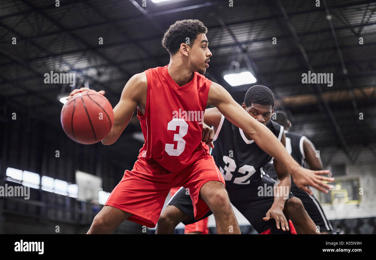Young male basketball player dribbling the ball, playing game in gymnasium Stock Photo