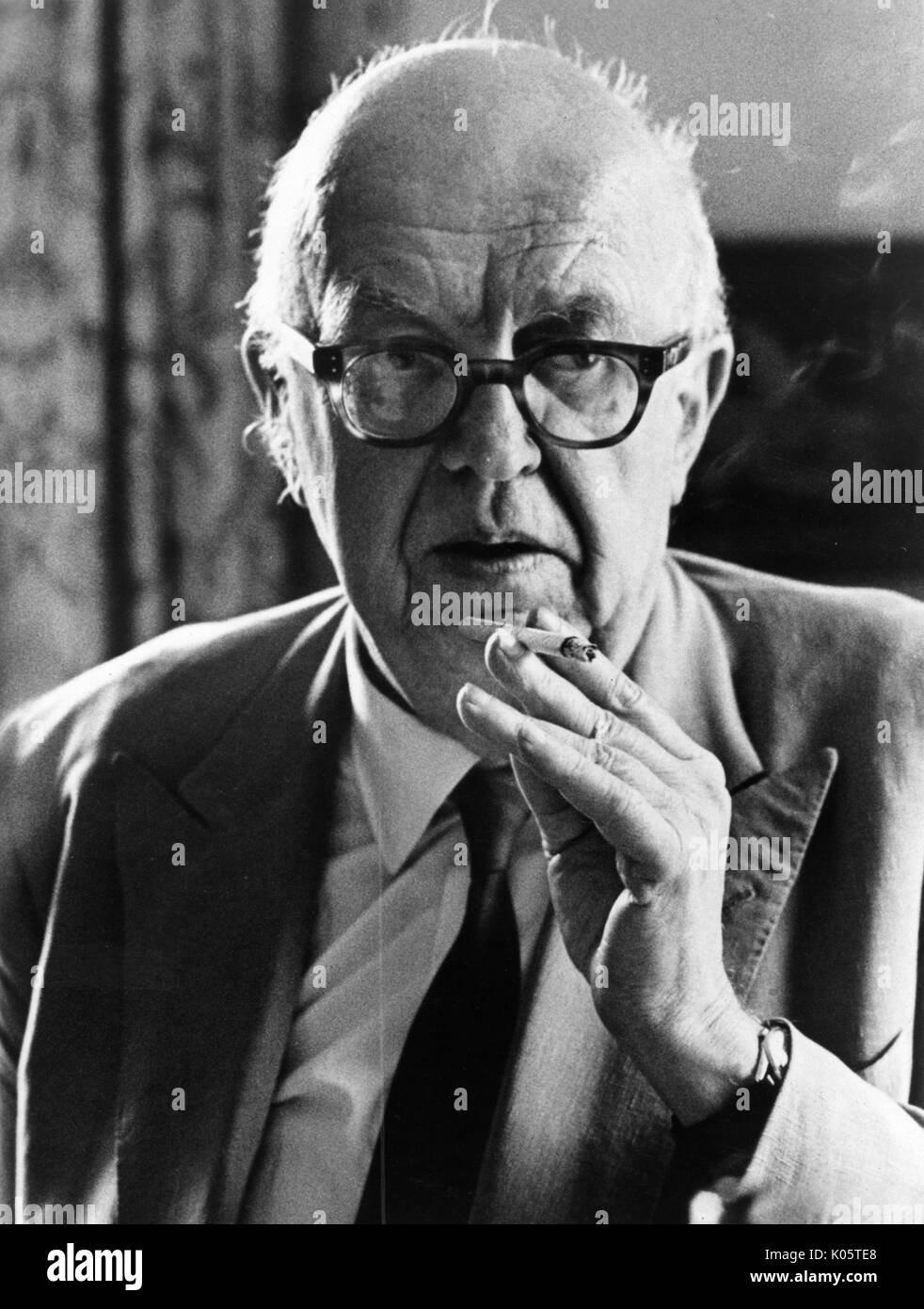 Half-length portrait of novelist, scientist, and civil servant CP Snow, wearing a dark suit and smoking a cigarette, with dark glasses, with a serious facial expression, 1971. Stock Photo