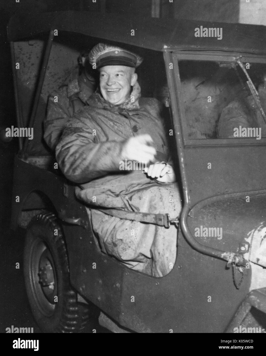 Full-body portrait of Milton S Eisenhower, former President of the Johns Hopkins University, seated in a military Jeep, wearing a large coat and a hat, with a smiling facial expression, gesturing his hands out of the car, 1970. Stock Photo