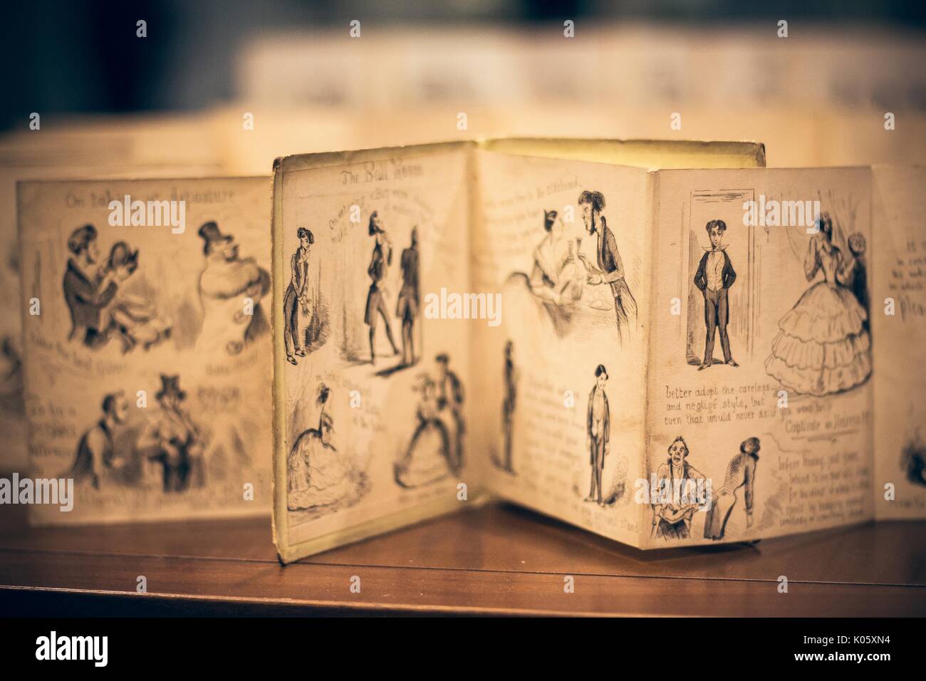 A browned and aged manuscript with illustrations of couples dancing, open on a table in the Special Collections department of a University library, 2016. Stock Photo