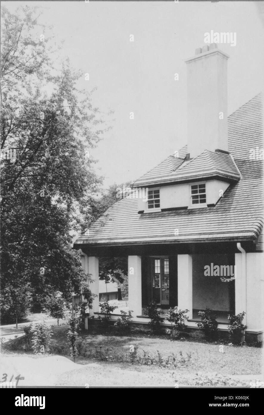 Side angle view of the side porch of a house near Roland Park and Guilford, the side porch has several light colored columns as support and there are some bushes placed around it, Baltimore, Maryland, 1910. Stock Photo