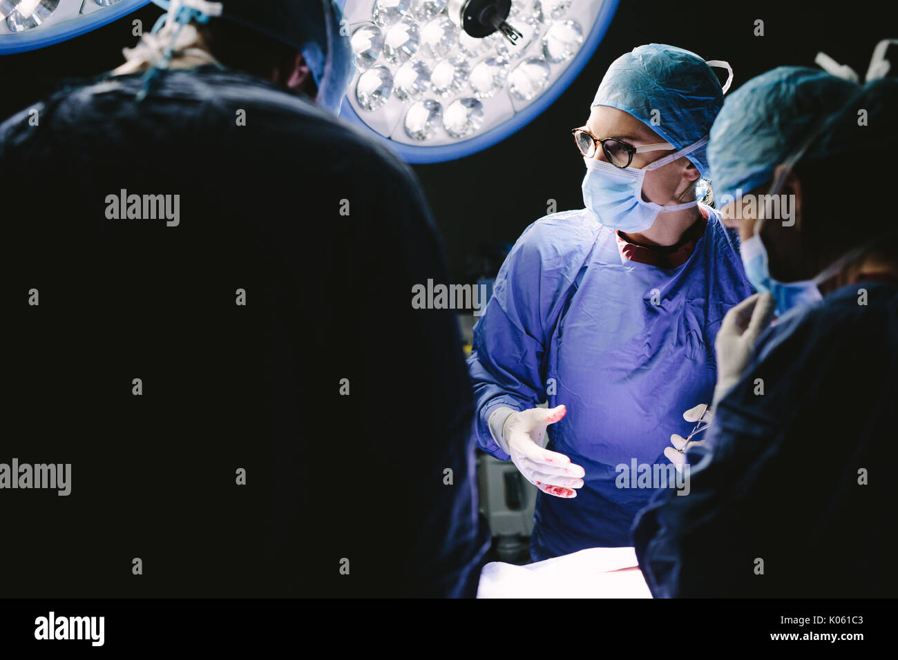 Surgeons team discussing during surgery. Group of doctors in hospital operation theater. Stock Photo