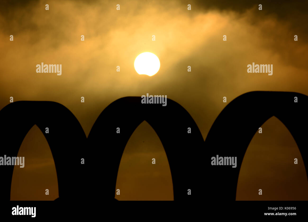 Partial Eclipse viewed briefly through hazy cloud over the silhouette of the Olympic Rings, Portland, Dorset, UK Credit: Finnbarr Webster/Ģ����ý Live News Stock Photo