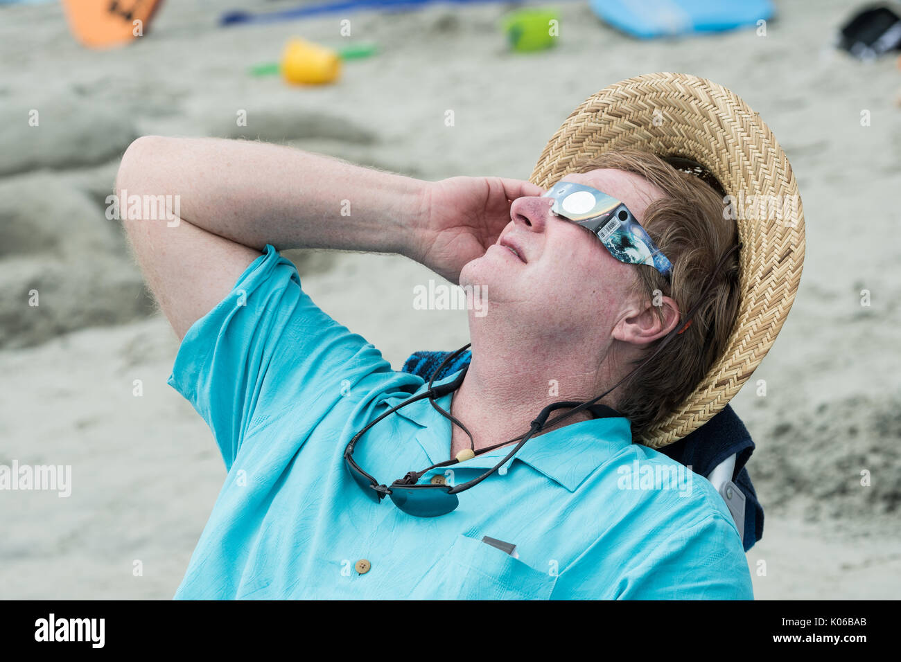 Charleston, Isle of Palms, USA. 21st Aug, 2017. A man relaxes in a beach chair as she view the total solar eclipse over the beach outside Charleston August 21, 2017 in Isle of Palms, South Carolina. The solar eclipse after sweeping across the nation crosses the Charleston area before heading over the Atlantic Ocean. Credit: Planetpix/Alamy Live News Stock Photo