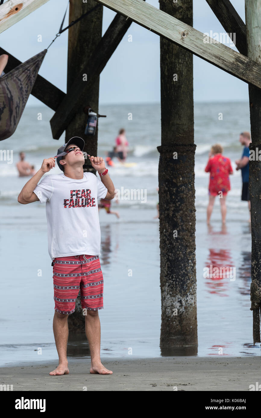 Charleston, Isle of Palms, USA. 21st Aug, 2017. A beach goer looks up at the total solar eclipse over the beach outside Charleston August 21, 2017 in Isle of Palms, South Carolina. The solar eclipse after sweeping across the nation crosses the Charleston area before heading over the Atlantic Ocean. Credit: Planetpix/Alamy Live News Stock Photo