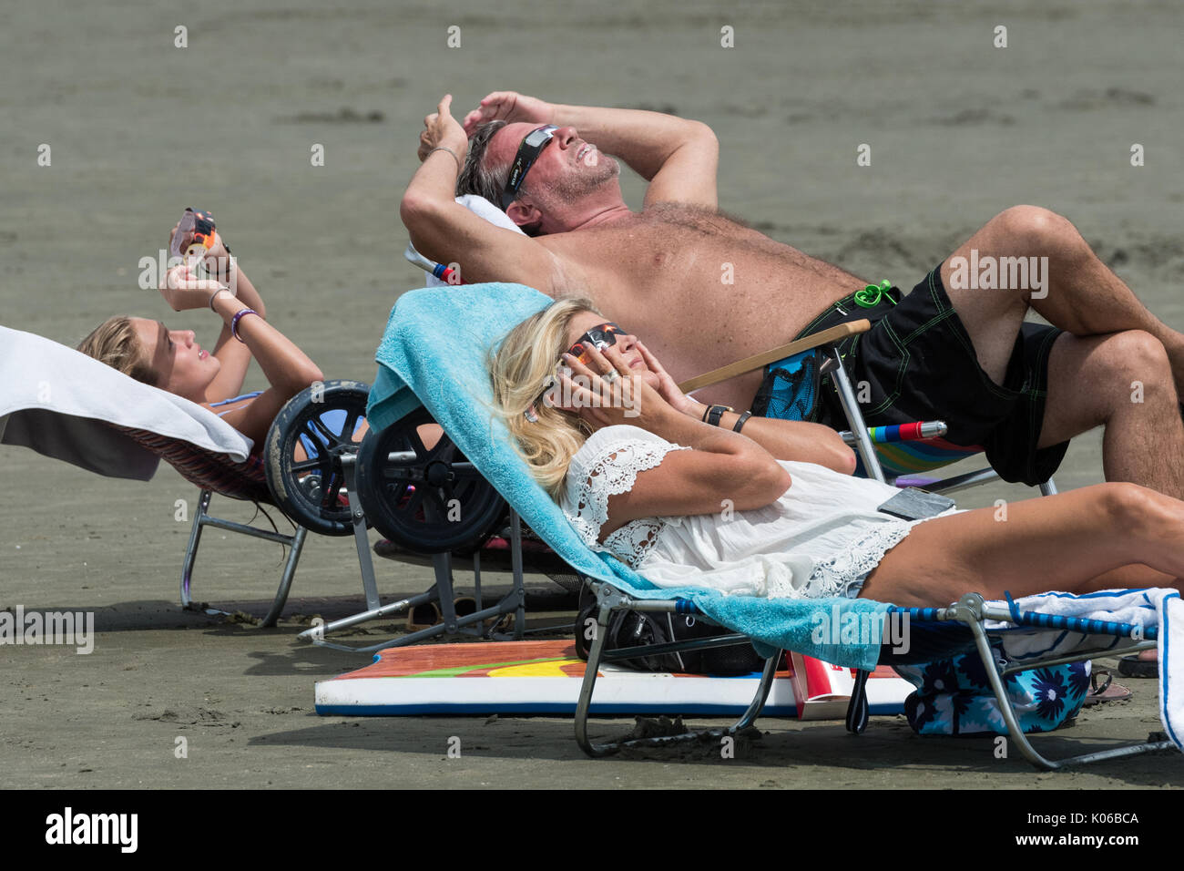 Charleston, Isle of Palms, USA. 21st Aug, 2017. A family relaxes in beach chairs as they view the total solar eclipse as it passes over the beach outside Charleston August 21, 2017 in Isle of Palms, South Carolina. The solar eclipse after sweeping across the nation crosses the Charleston area before heading over the Atlantic Ocean. Credit: Planetpix/Alamy Live News Stock Photo