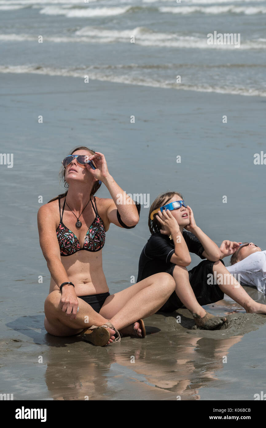 Charleston, Isle of Palms, USA. 21st Aug, 2017. A family sits along the shoreline as they view the total solar eclipse as it passes over the beach outside Charleston August 21, 2017 in Isle of Palms, South Carolina. The solar eclipse after sweeping across the nation crosses the Charleston area before heading over the Atlantic Ocean. Credit: Planetpix/Alamy Live News Stock Photo