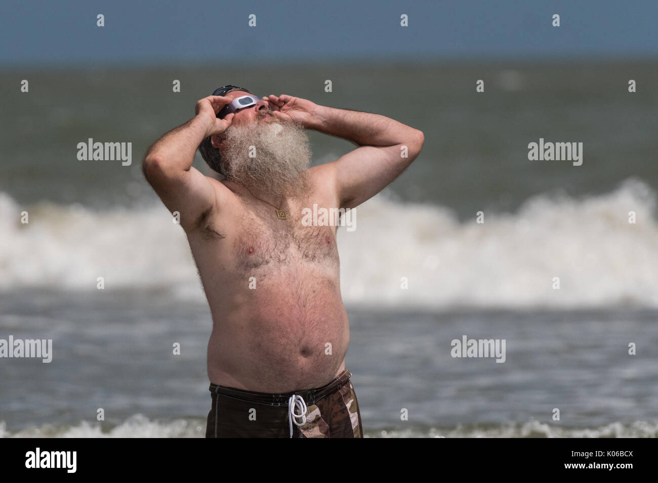 Charleston, Isle of Palms, USA. 21st Aug, 2017. A man watches the total solar eclipse standing in the water as it passes over the beach outside Charleston August 21, 2017 in Isle of Palms, South Carolina. The solar eclipse after sweeping across the nation crosses the Charleston area before heading over the Atlantic Ocean. Credit: Planetpix/Alamy Live News Stock Photo