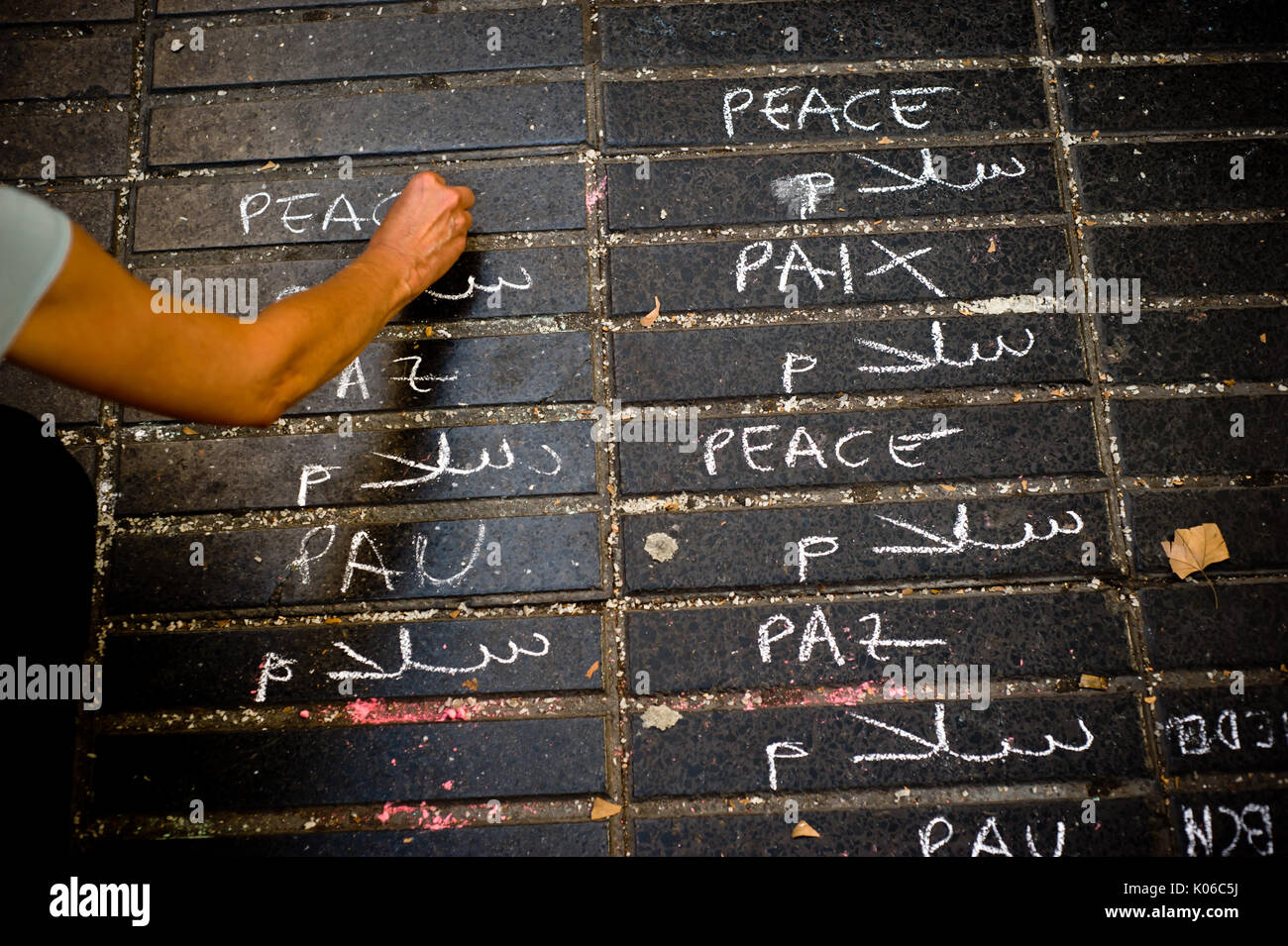 Barcelona, Catalonia, Spain. 21st Aug, 2017. A woman writtes in several languages the word 'peace' on the floor of Las Ramblas in Barcelona the same day that Younes Abouyaaqoub, identified as driver of van that sped down Las Ramblas on Thursday, has been shot dead by Catalan police officers in the village of Subirats. Credit: Jordi Boixareu/ZUMA Wire/Alamy Live News Stock Photo