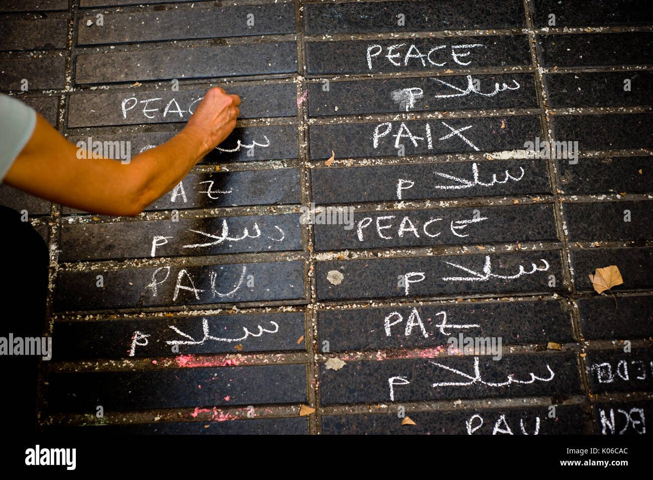 Barcelona, Spain. 21st Aug, 2017. A woman writtes in several languages the word 'peace' on the floor of Las Ramblas in Barcelona the same day that Younes Abouyaaqoub, identified as driver of van that sped down Las Ramblas on Thursday, has been shot dead by Catalan police officers in the village of Subirats. Credit: Jordi Boixareu/Alamy Live News Stock Photo