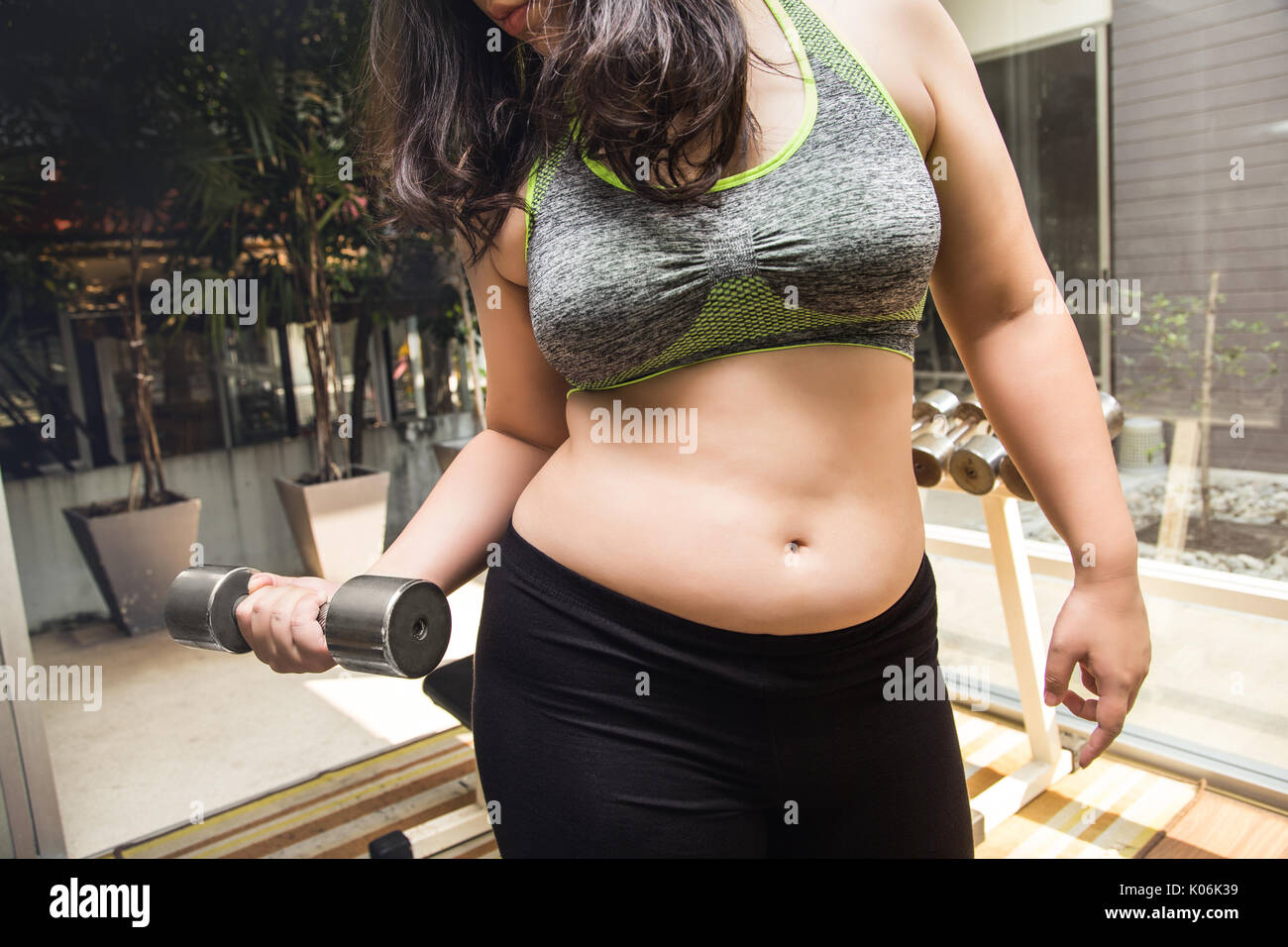 Fat woman weight loss lifting dumbbell in fitness gym Stock Photo