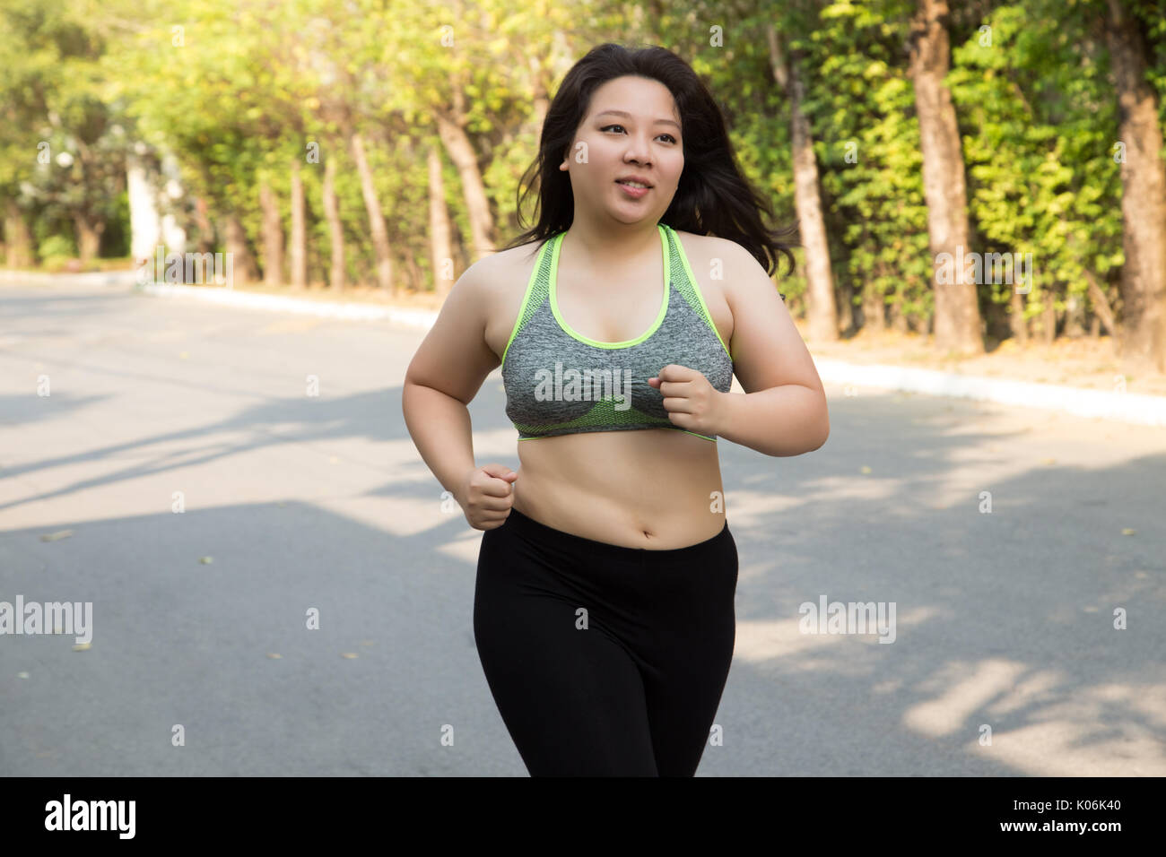 Fat woman running exercise smile face in park weight loss concept Stock Photo