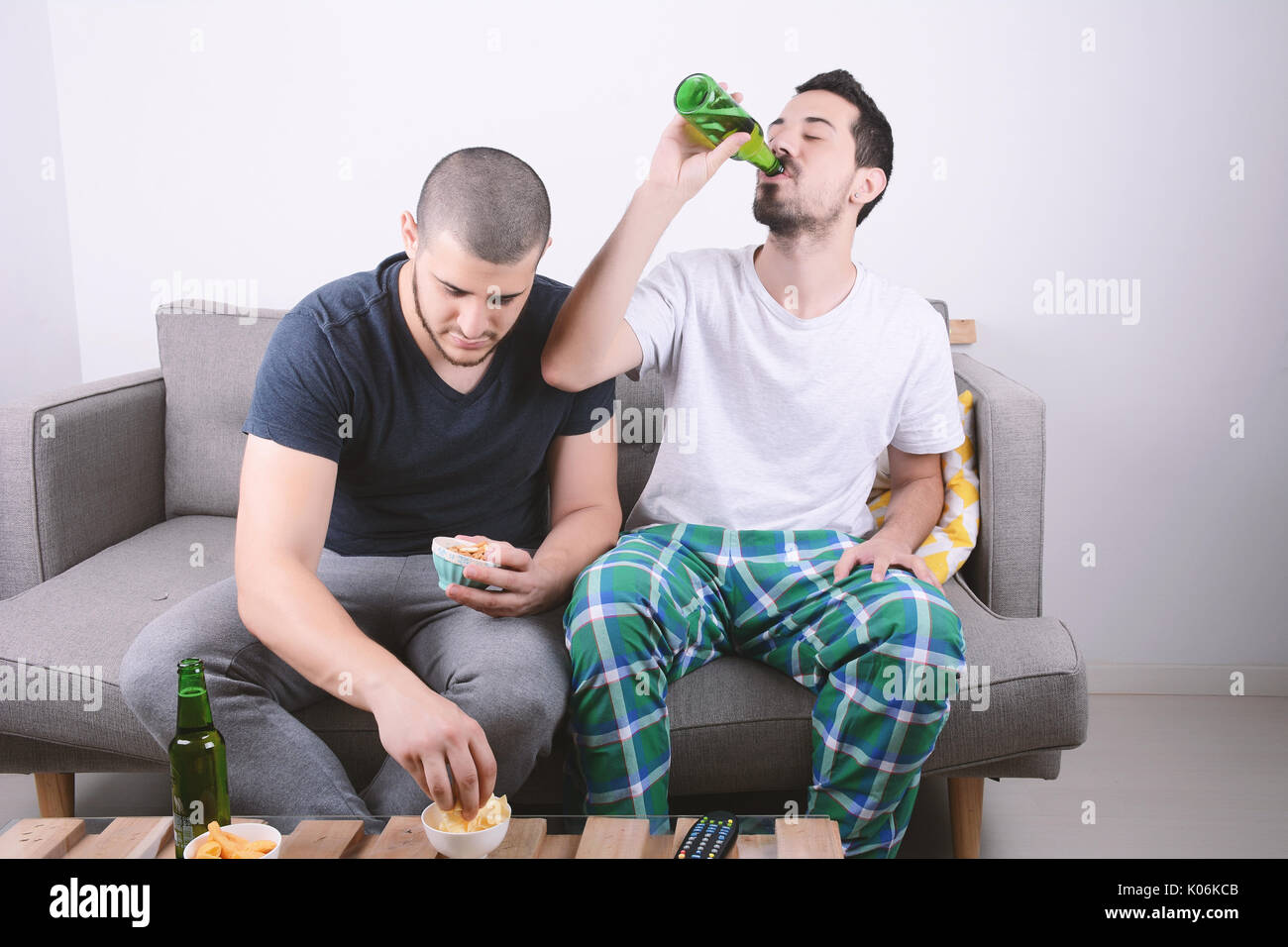 Two friends eating snacks and drinking beer. Indoors Stock Photo Alamy