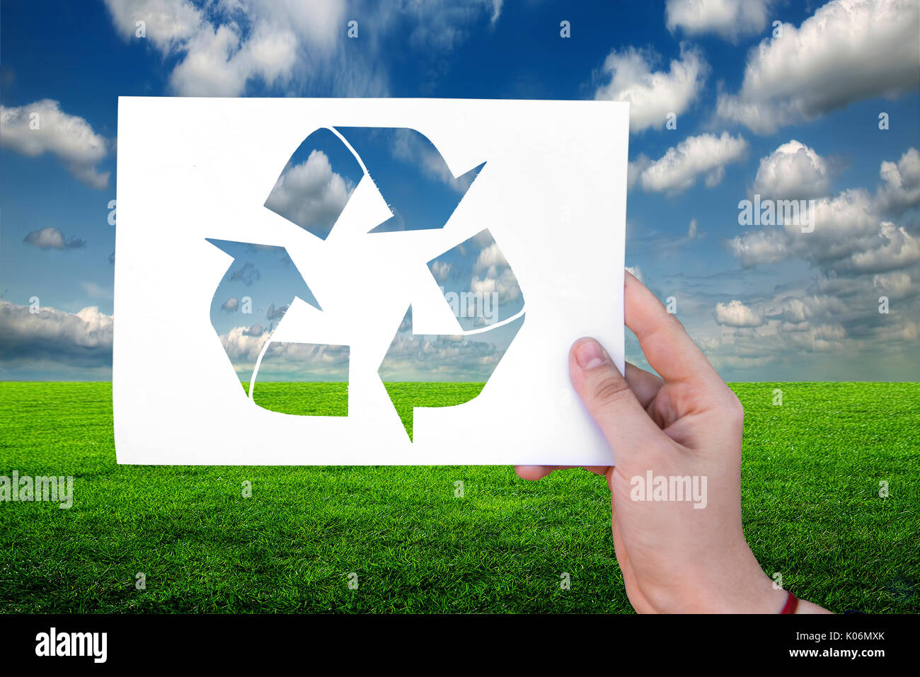 Ecology sign on white sheet on grass background in hand Stock Photo
