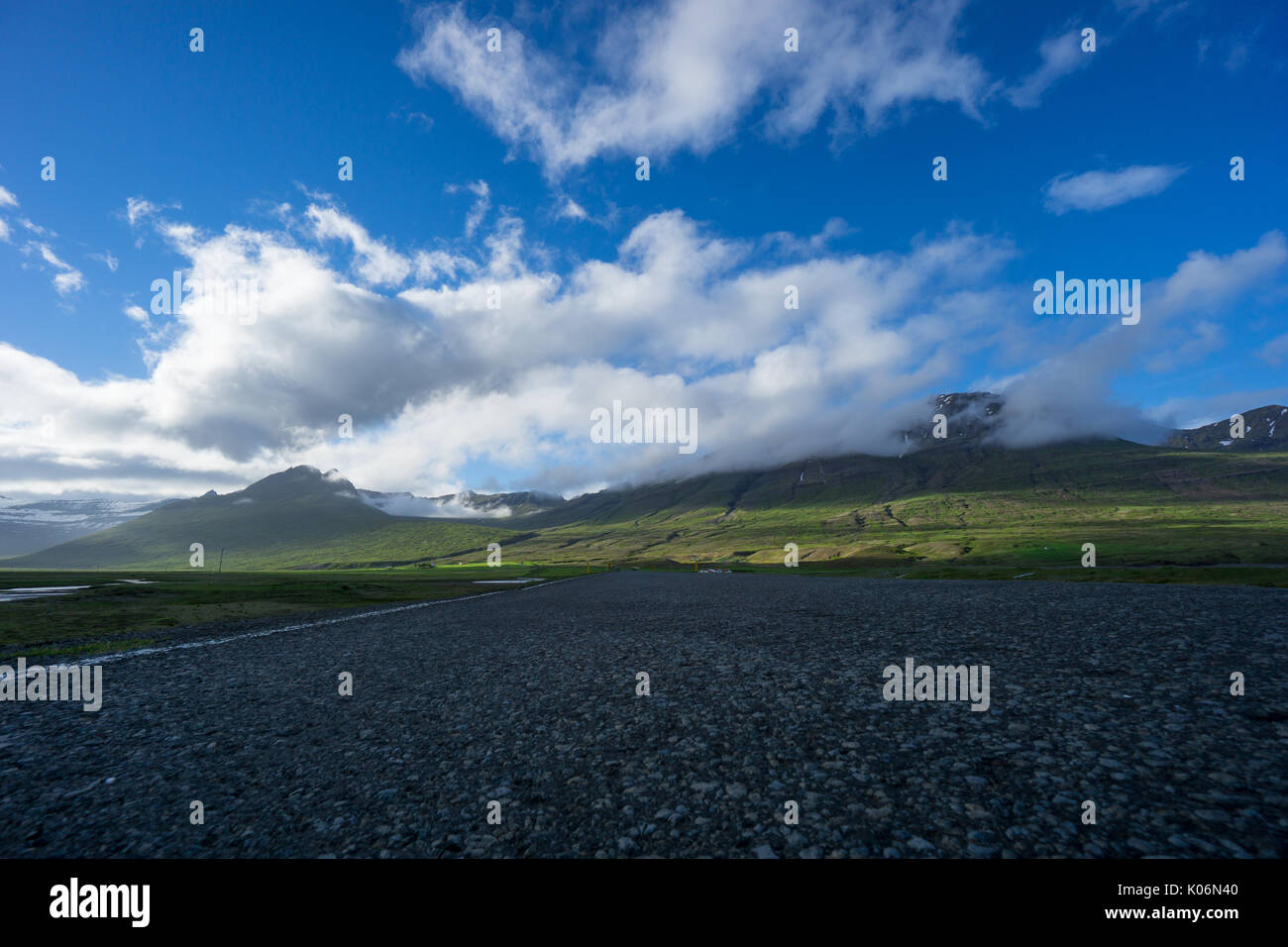 Iceland - Empty endless highway route 1 at shining green mountains Stock Photo