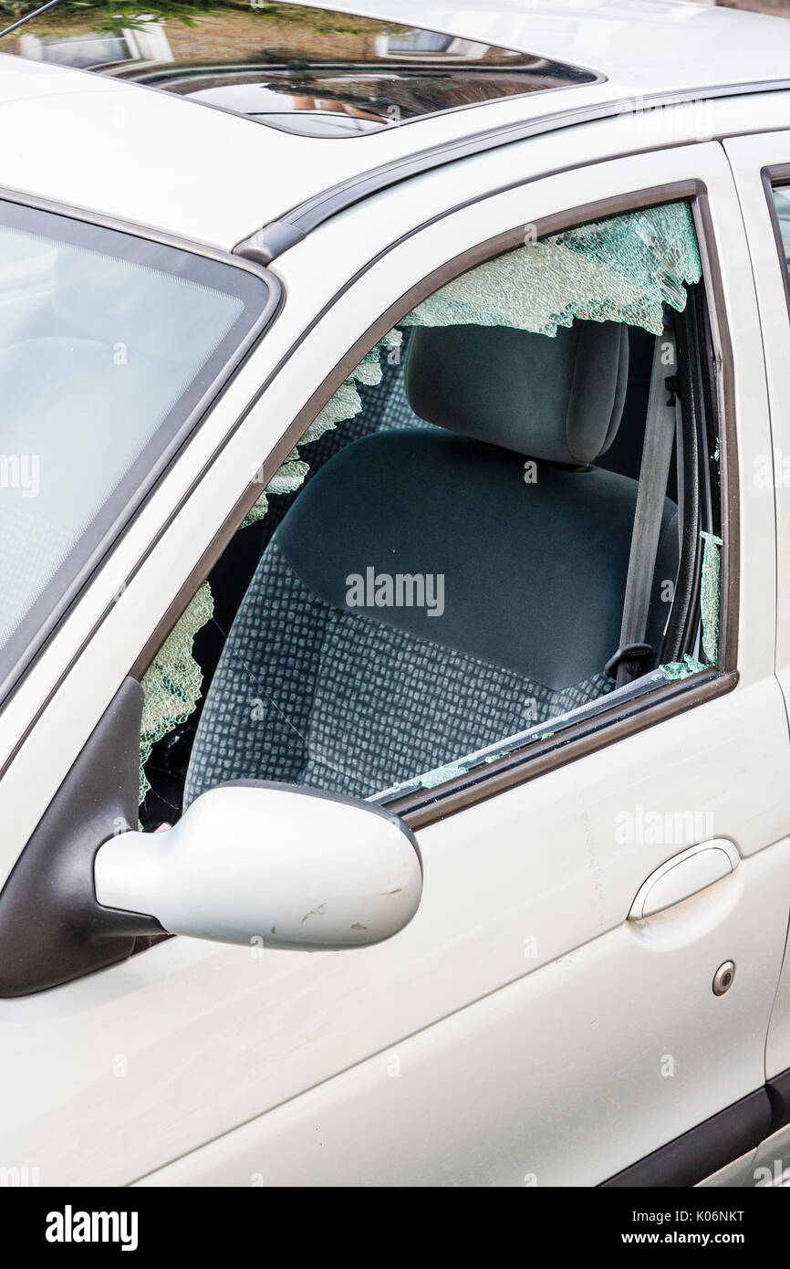 Close up of passenger side window of small white car smashed after robbery. Stock Photo