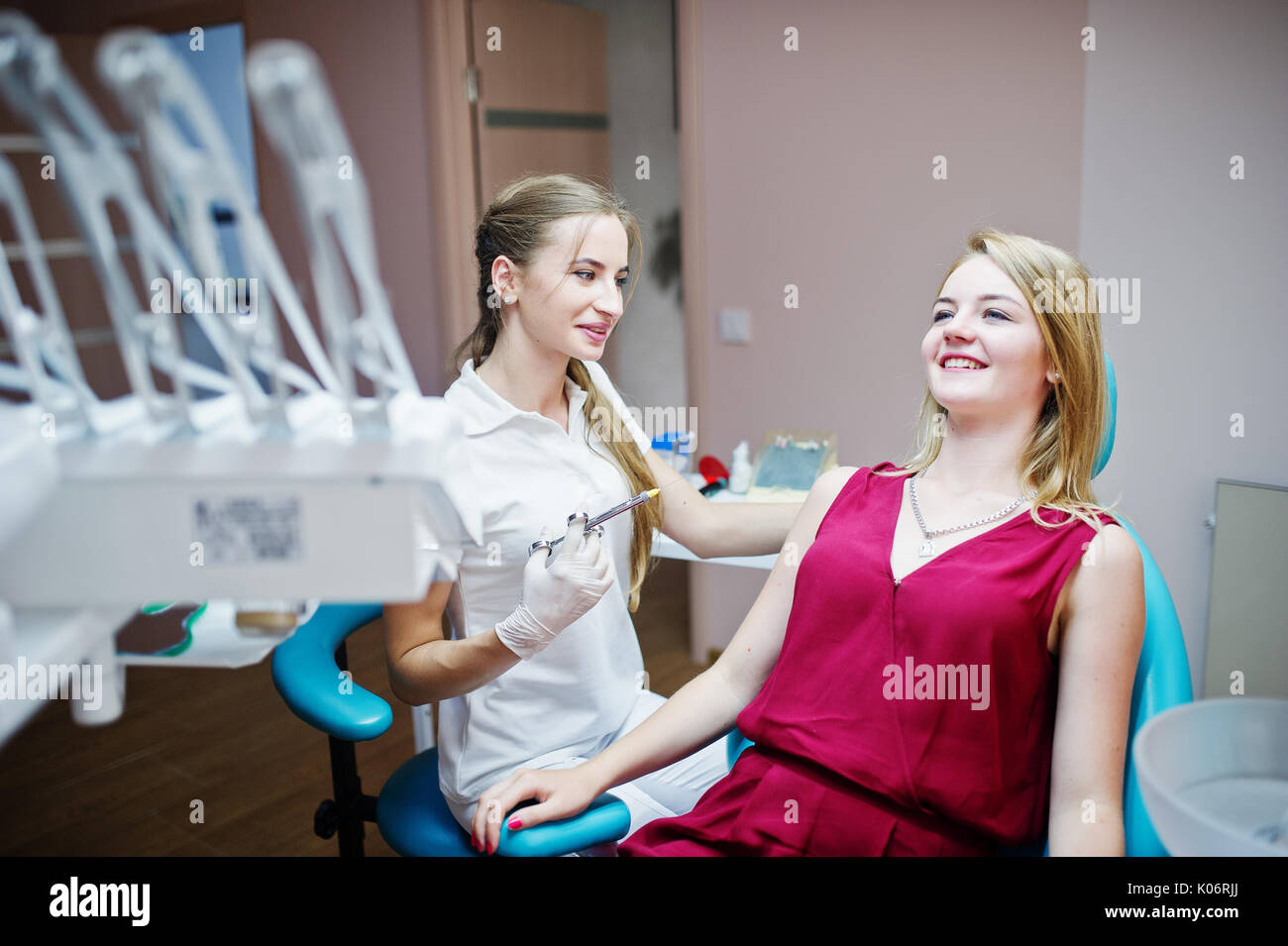 Attractive female orthodontist injecting anesthesia to her patient in a