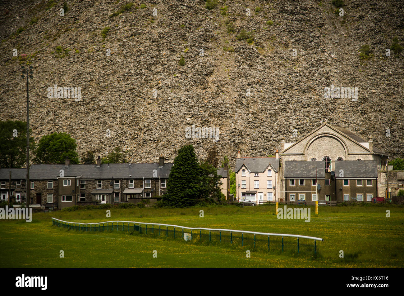 Mountains of slate waste towering over the houses, chapel  and rugby pitch in Blaenau Ffestiniog, Gwynedd, North Wales UK Stock Photo