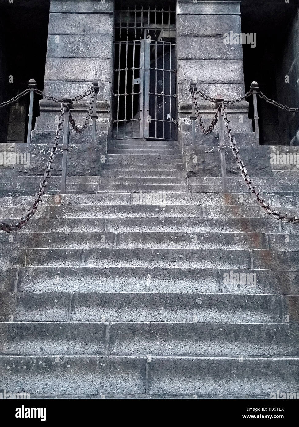 old stone staircase with chain railing and iron gate Stock Photo