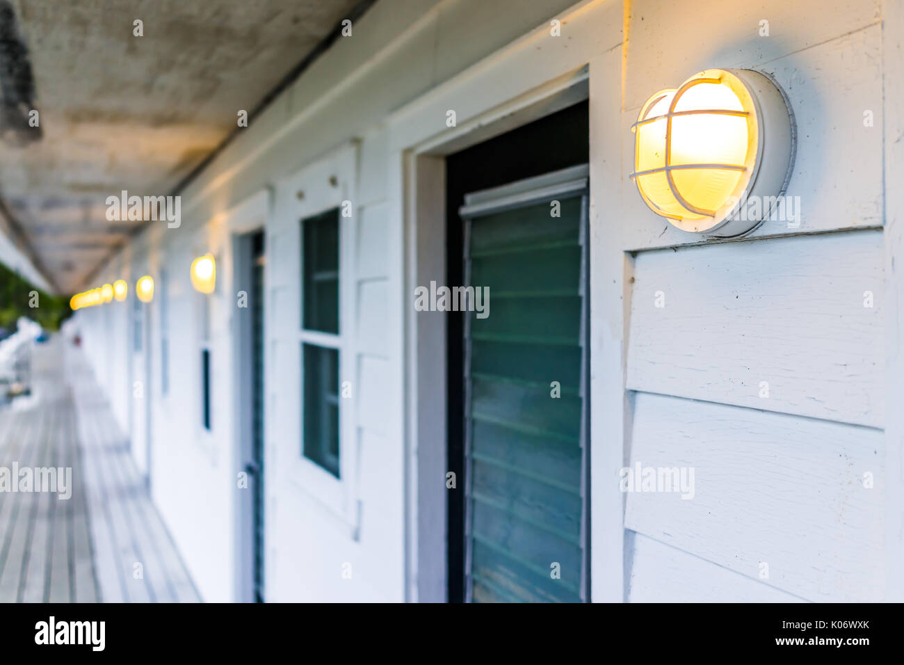 Row of hotel or motel doors outside with illuminated lights lamps in evening Stock Photo