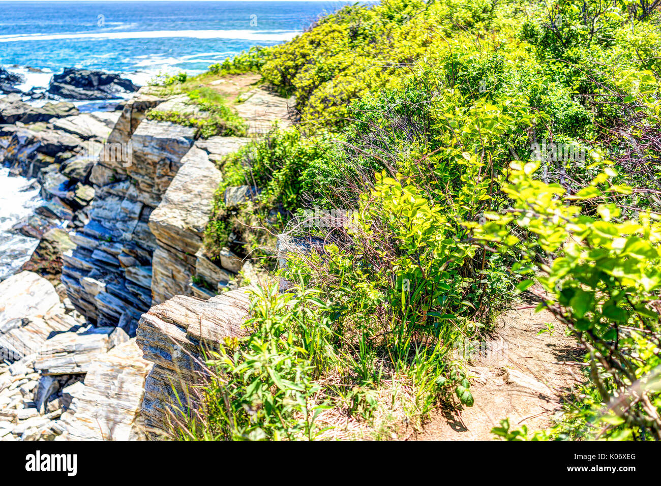Trail on cliff with green bushes by Portland Head Lighthouse in Fort Williams park in Cape Elizabeth, Maine during summer Stock Photo