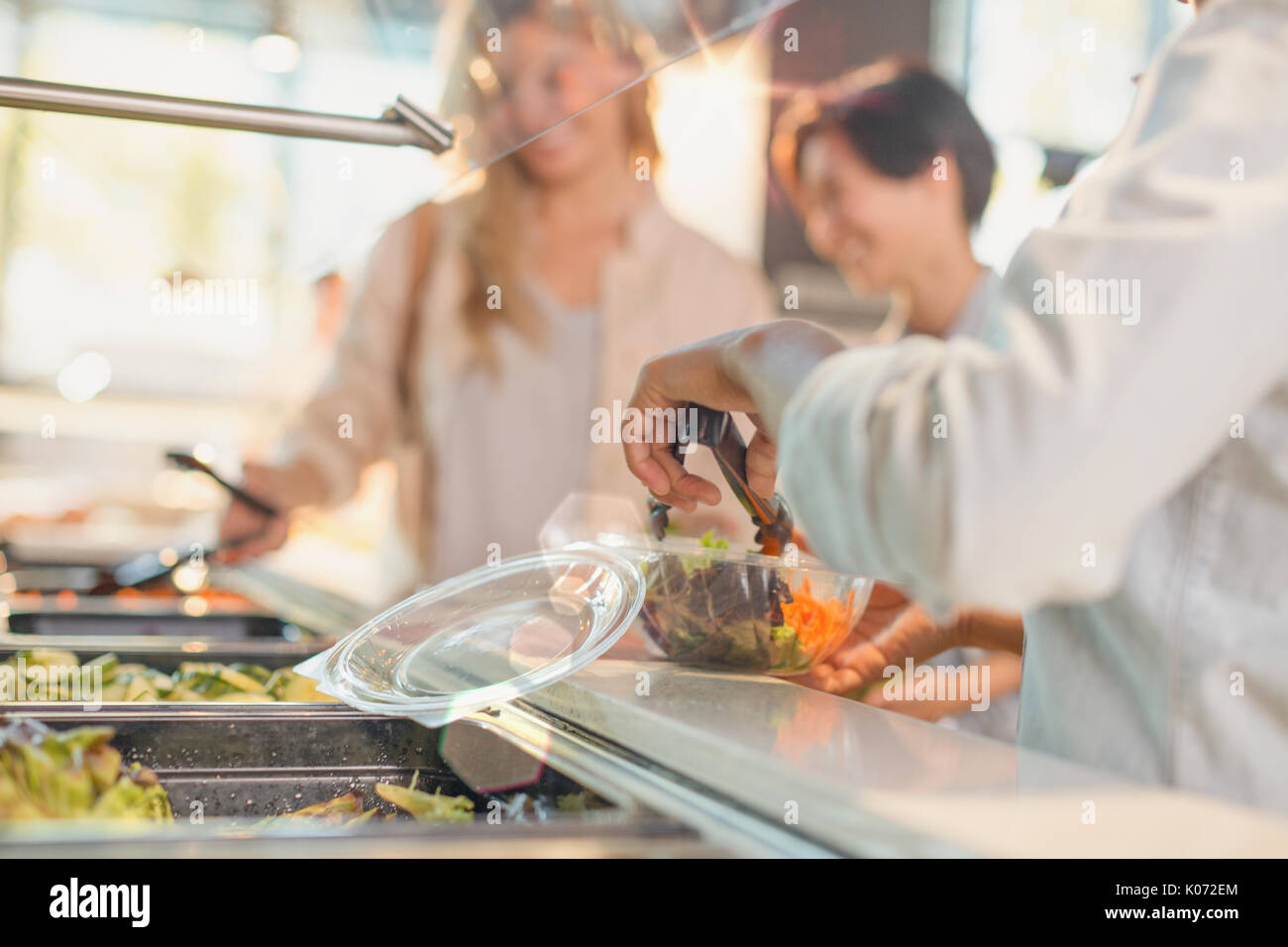 Young woman serving salad at salad bar in grocery store market Stock Photo