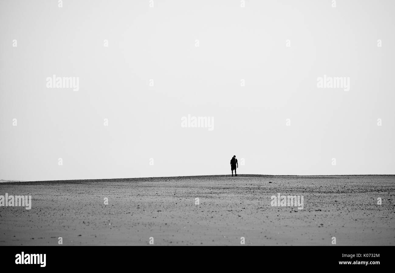 Lone male walker on a North Norfolk beach. Stock Photo