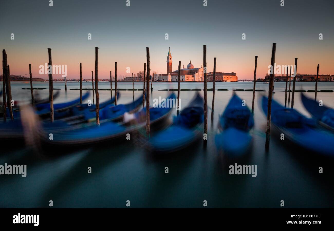 Venice, Veneto, Italy. View of San Giorgio cathedral during a quiet winter sunset, with gondolas on the foreground. Stock Photo