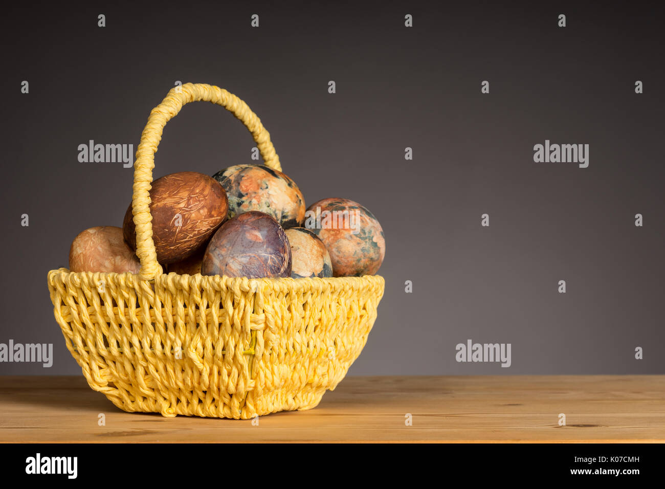 Multicolored hand painted easter eggs in the yellow basket Stock Photo