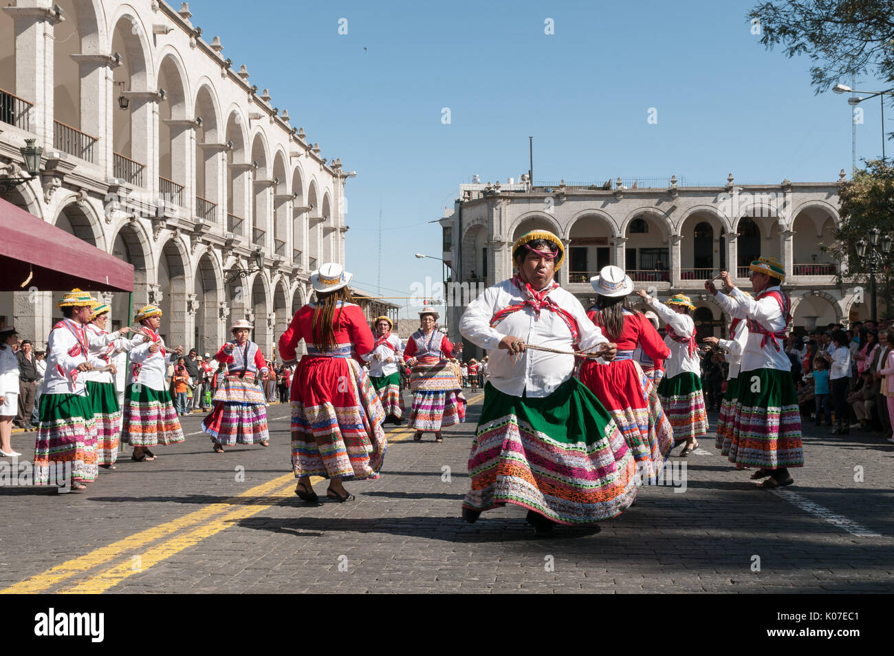 A group of farmers dressed in traditional clothing dances along a cobbled street near Plaza de Armas, Arequipa, Peru. Stock Photo