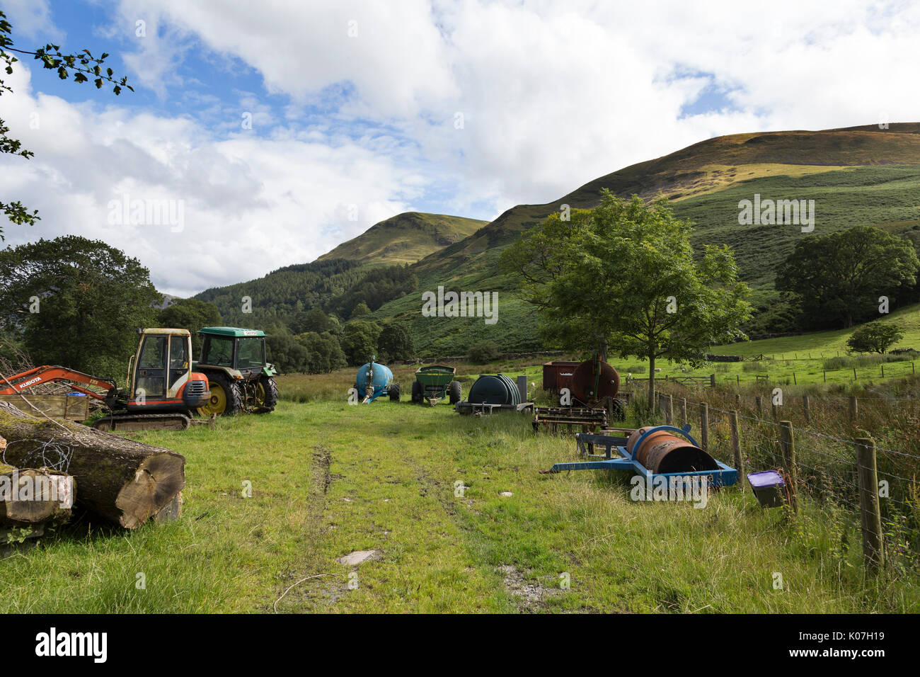 Farm tractors and other equipment at Hudson Place, Loweswater, Lake District, Cumbria, England. Burnbank Fell and Carling Knott are also shown. Stock Photo