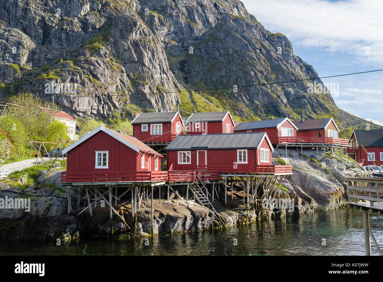 Red wooden rorbus fishermen's huts and buildings on stilts by sea in fishing village of Å, Moskenes, Moskenesøya Island, Lofoten Islands, Norway Stock Photo