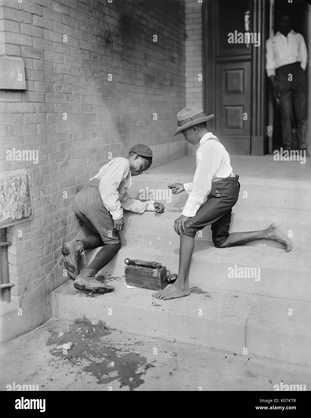Two African American shoe shine boys playing a gambling game in America     Date: circa 1901 Stock Photo