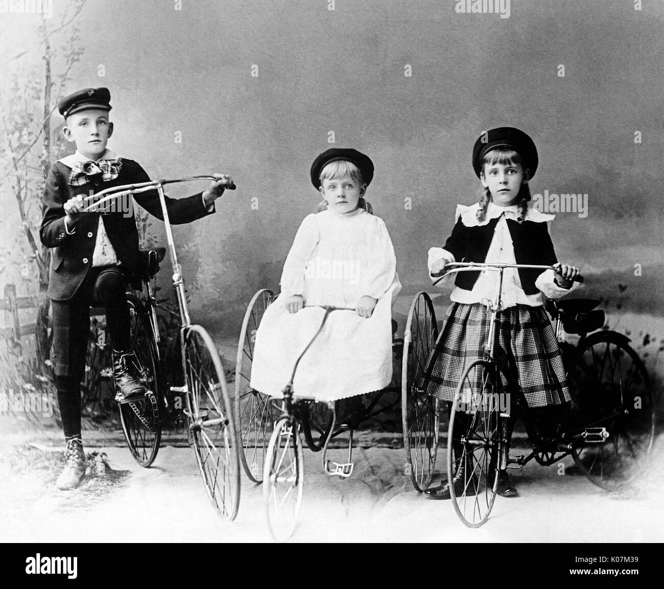 Three children posed with bicycle and tricycles in America Stock Photo