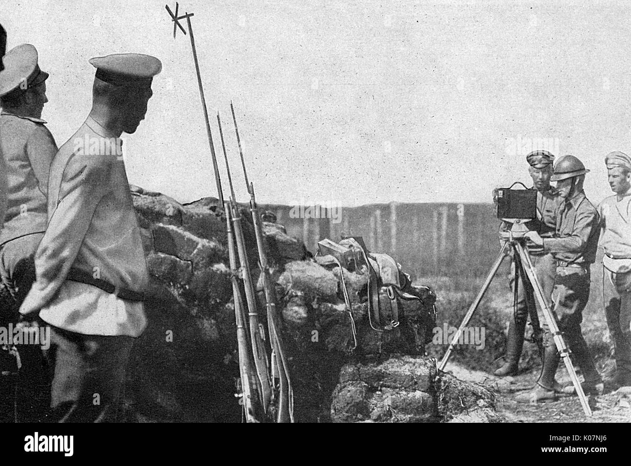 Russian soldiers on the eastern front, Russia, during the First World War. The cross shape on top of a stick is a wind gauge, designed to show whether the wind was in the right direction for a potential gas attack from the German lines. The man on the right with a camera on a tripod is probably Donald C Thompson (1885-1947).      Date: circa 1917 Stock Photo